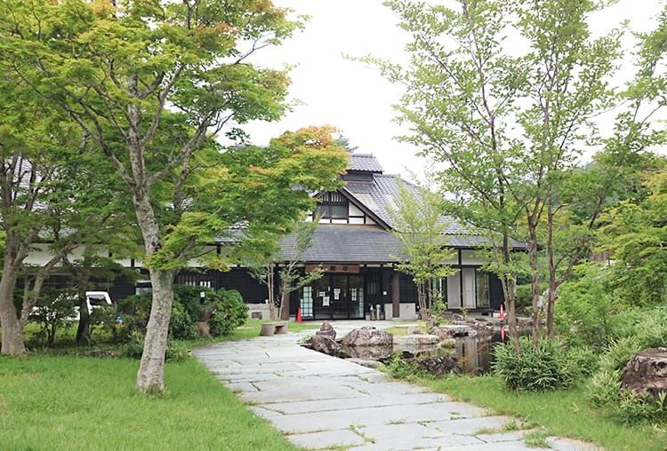 木々や芝生に囲まれており、昔ながらの日本家屋の雰囲気が漂ういわなの郷の外観写真