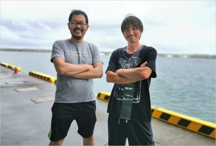 海を背景に開沼博さんと菊地基文さんが並んで腕を組んでいる写真