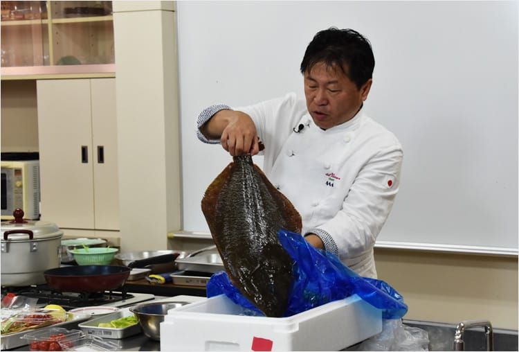 奥田政行さんが新鮮なヒラメを発泡スチロールの箱から取り出している様子の写真