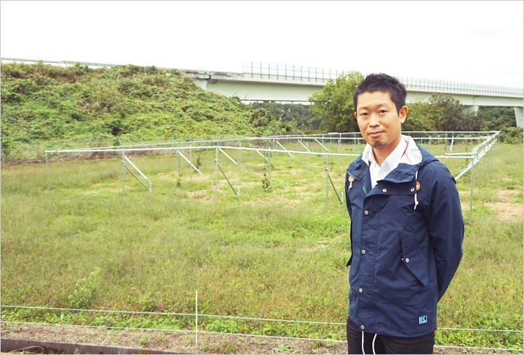 広い緑豊かな敷地を背景に栗城英雄さんがほほえんでいる写真
