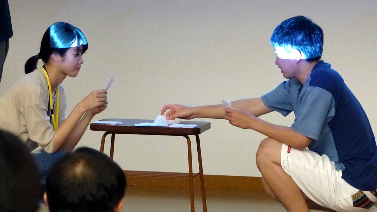 男女の大学生2人が、ワークショップの参加者が考案したカードゲームを用いて遊んでいる様子