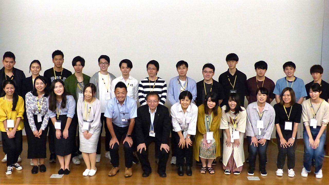 白い壁を背景に、参加した学生と講師らが並んでいる集合写真