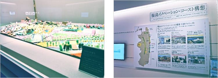 ガラスの中に展示されている、福島の町を再現した色とりどりのジオラマの写真と、福島イノベーション・コースト構想と題された取り組みを紹介する展示パネルの写真