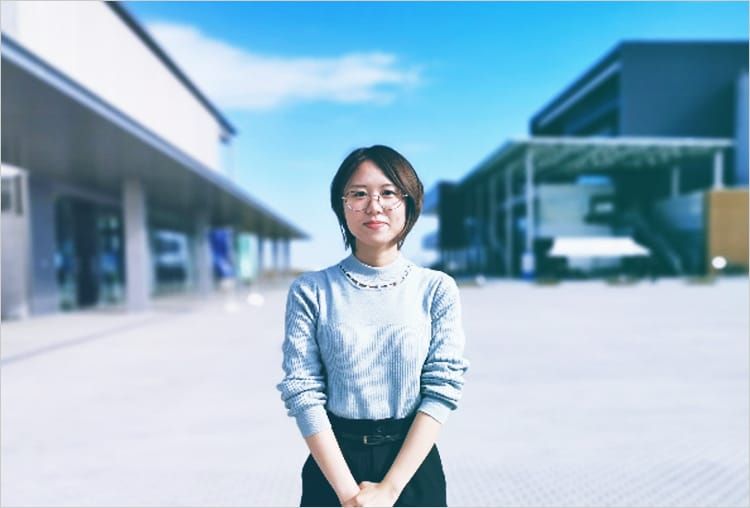 伝承館に来館した浪江町出身の女性が、伝承館の前でカメラに向かって微笑んでいる写真