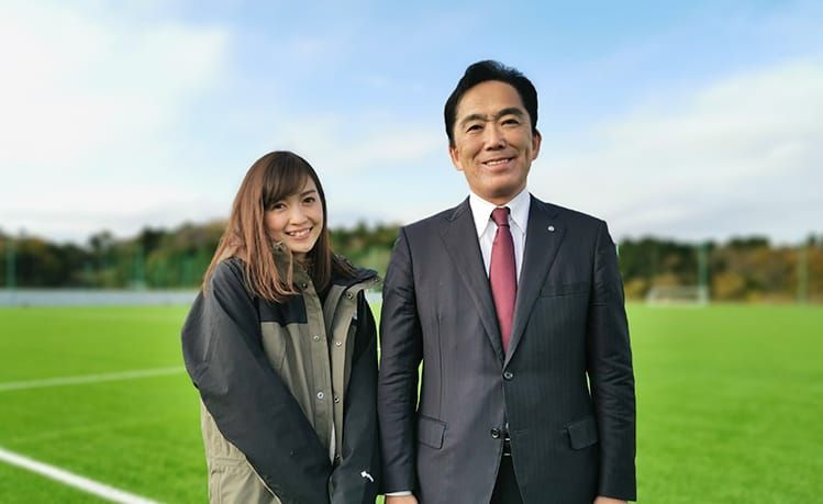高橋万里恵さんと遠藤智広野町長がサッカーグラウンドで笑顔を浮かべ並んでいる様子の写真