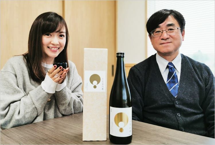 会議室で高橋万里恵さんと三瓶雅弘さんが「天の希」を挟むように座り、笑みを浮かべている写真