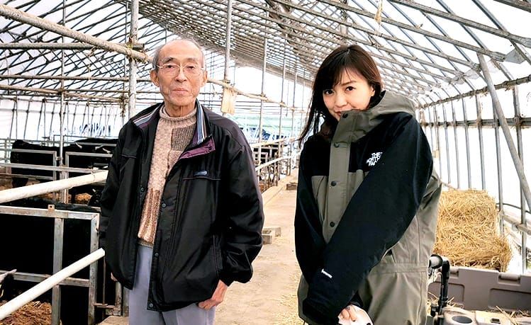 牛舎の中で小林稔さんと高橋麻里江さんが並んでいる様子の写真