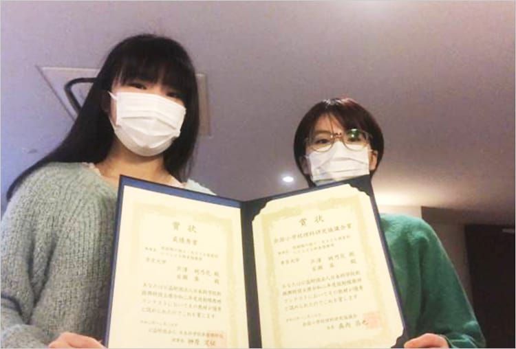 最優秀賞を受賞した帝京大学の学生二人が賞状を持ちながら並んでいる写真