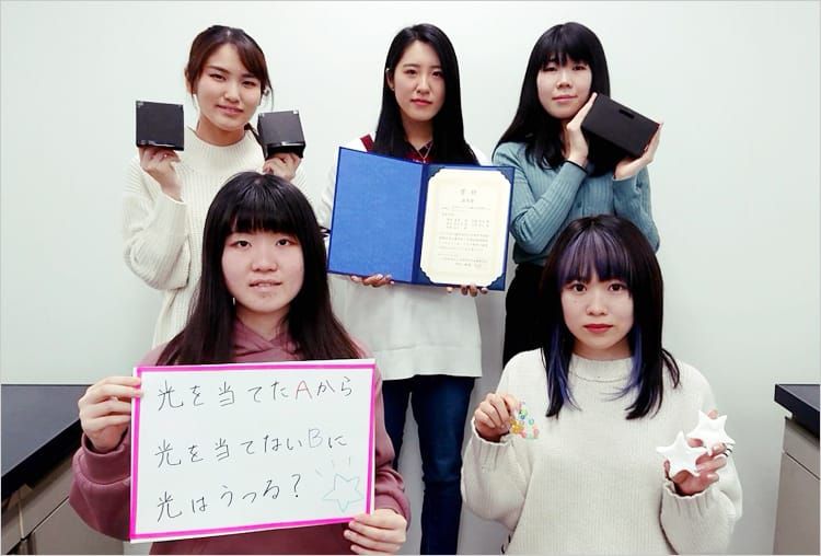 受賞した女子学生たちが賞状や資料を手に持ち、にこやかに並んでいる写真