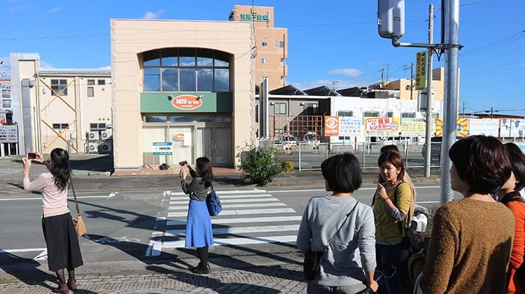 震災の影響を受け、変化してしまった街並みを撮影する女性のツアー参加者らの様子。