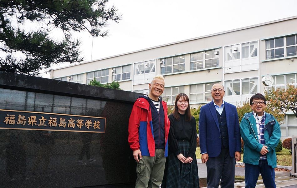 福島県立福島高等学校の正門の横で、左からウド鈴木さん、齊藤美緑さん、原尚志さん、天野ひろゆきさんが並び笑顔を浮かべている写真