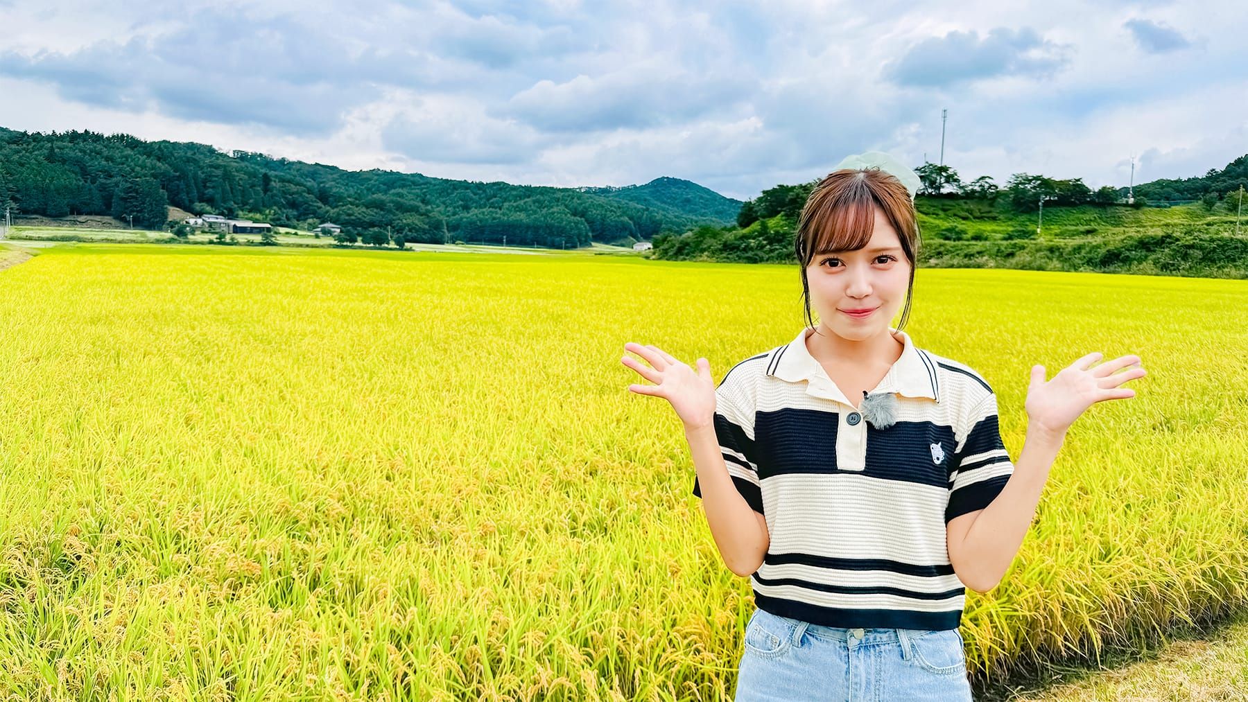 諸橋沙夏さんがあぶくまもちの稲穂を背にしている様子