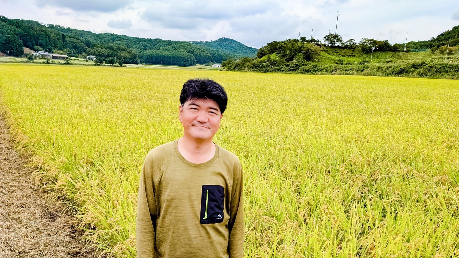 あぶくまもちの稲穂をバックに佇む青田豊実さん
