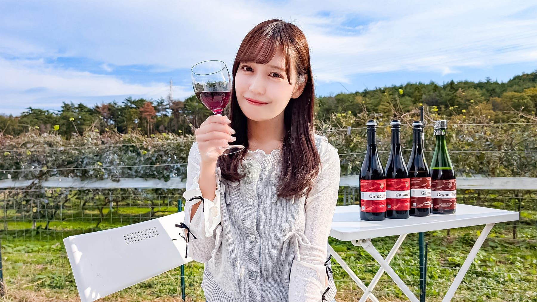 赤スパークリングワインを片手に諸橋さんがポーズをとっている写真