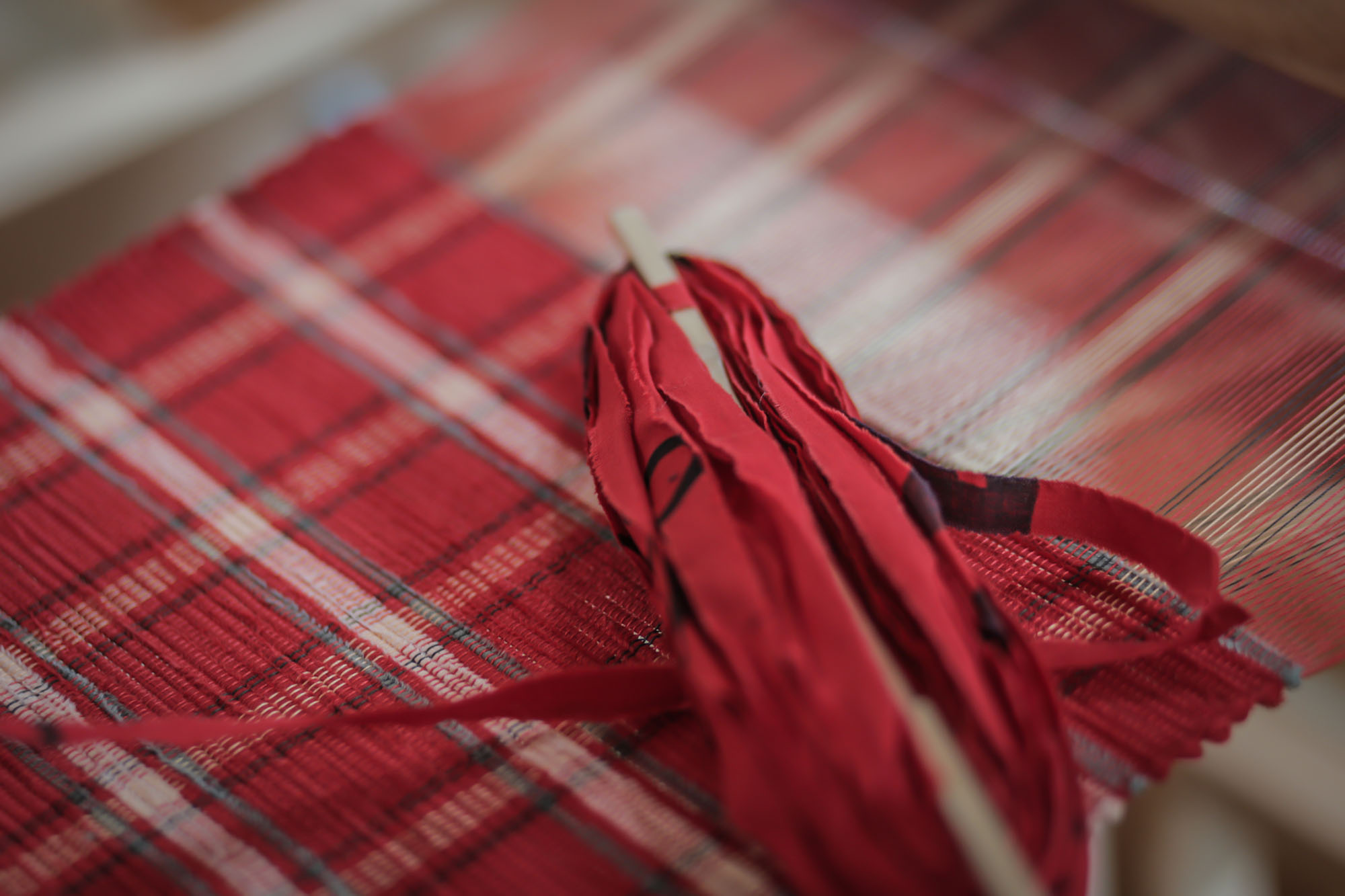布を細く裂いた横糸を、経糸を通した織り機で一段一段ていねいに織り込んで作る裂き織