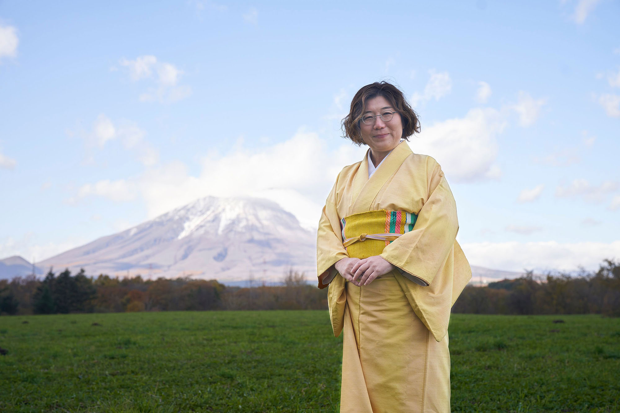 やわらかさの中に芯の強さを感じさせる石頭悦代表取締役。後ろにそびえるのは「南部富士」と呼ばれる岩手山